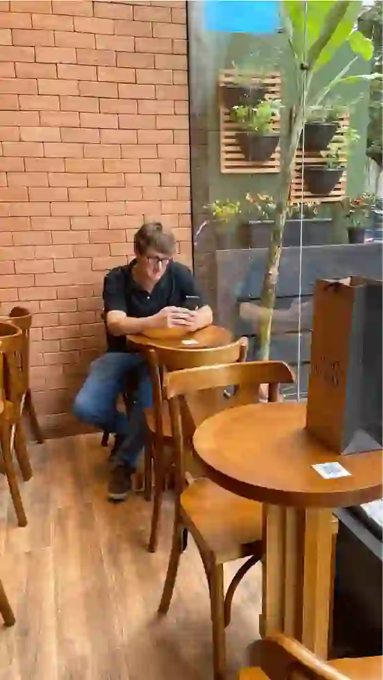 Homem sentado a mesa mexendo no celular